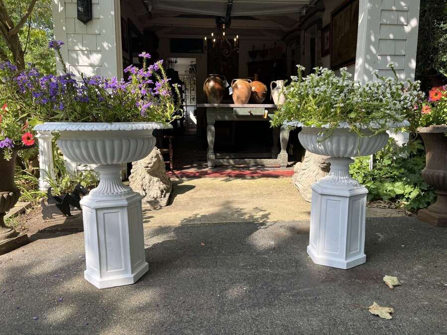 Pair of white painted cast iron garden urns on pedestals