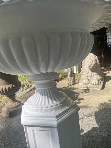 Pair of white painted cast iron garden urns on pedestals